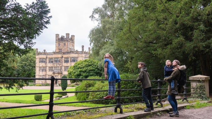 Visitors in the garden at Gawthorpe Hall, Lancashire: a child stands on railings with the house in the background